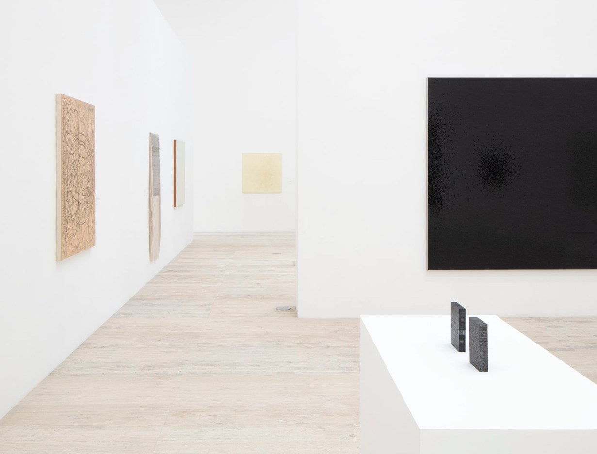 Sala con un dibujo sobre madera, un monocromo negro y dos piezas escultóricas oscuras