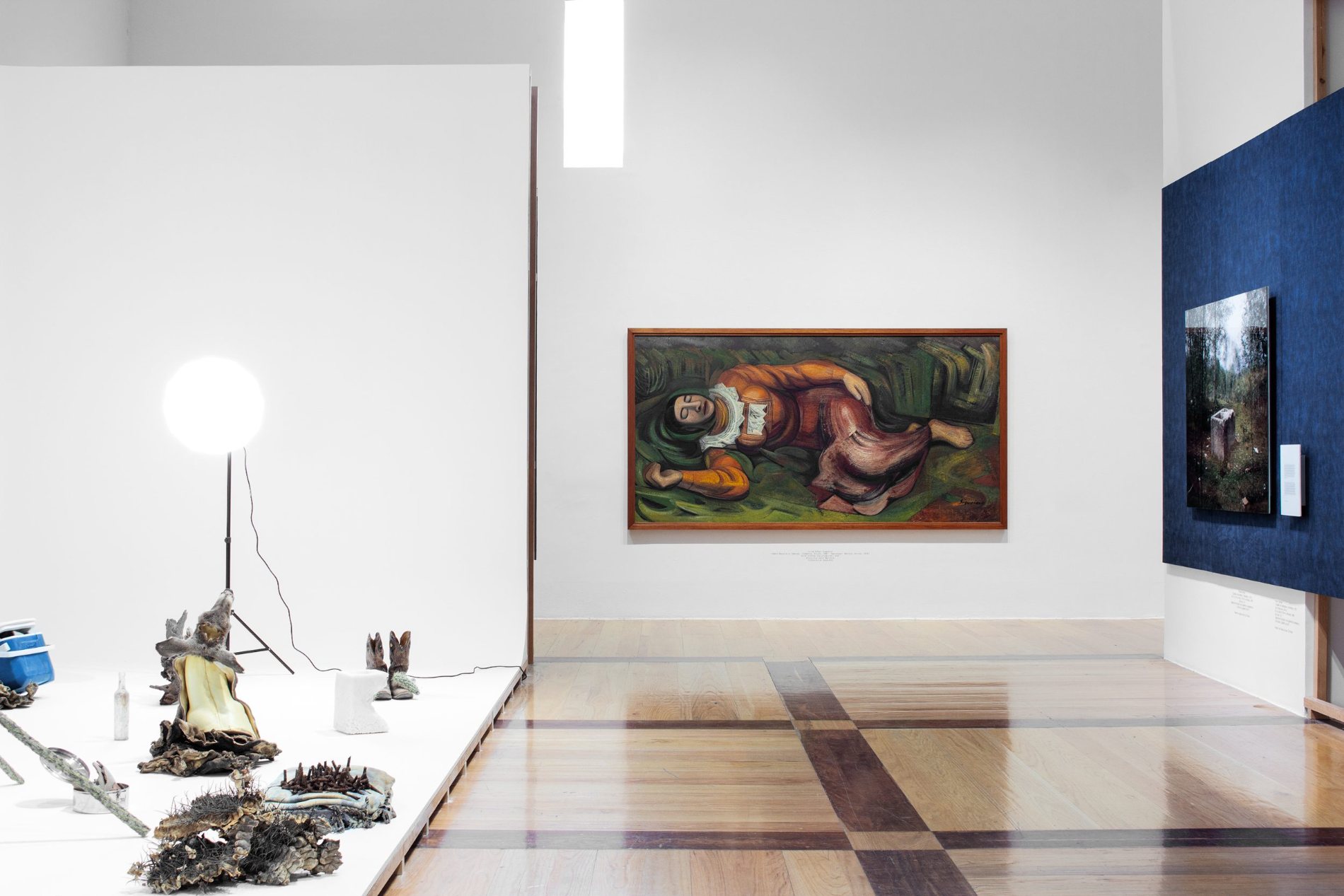 Sala blanca con una obra de neón, un texto grabado en la pared y una gran instalación textil anaranjada suspendida