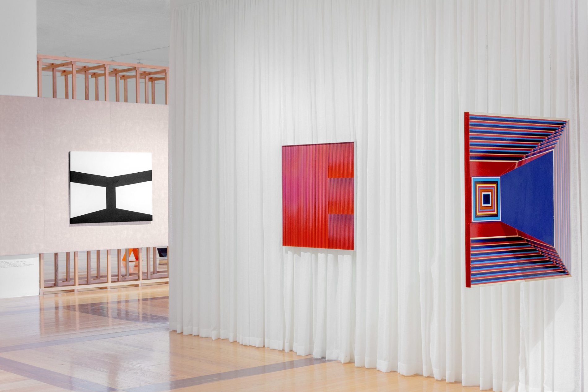 Sala con un díptico de tonos naranjas y azules rematado por las palabras Trabajadores honrados y Muchachos alegres, una escultura vertical sobre una esfera y tres fotografías