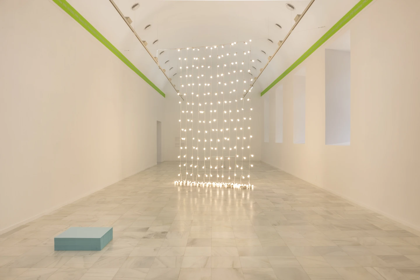 Alfombra rectangular de caramelos azul turquesa extendida sobre el suelo de mármol de una sala blanca