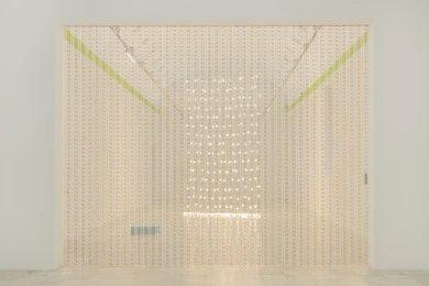 Cortina de cuentas iluminada de frente, con destellos de luz al fondo