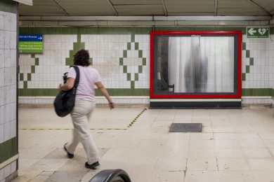Valla de Gonzalez-Torres con marco rojo en una estación de metro de Madrid, con una viajera pasando